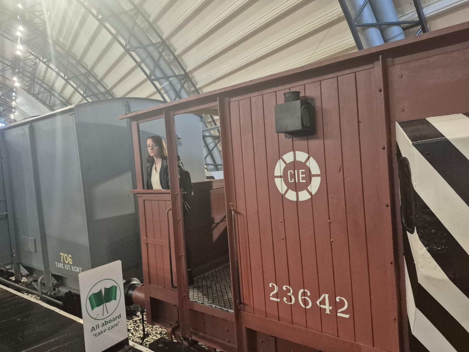 At the front of the image: Bethan is on a train wagon in front of a sign that reads 'Alll aboard take care'